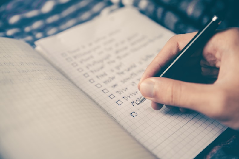 An open planner with a pen resting on a wooden desk near a coffee cup.