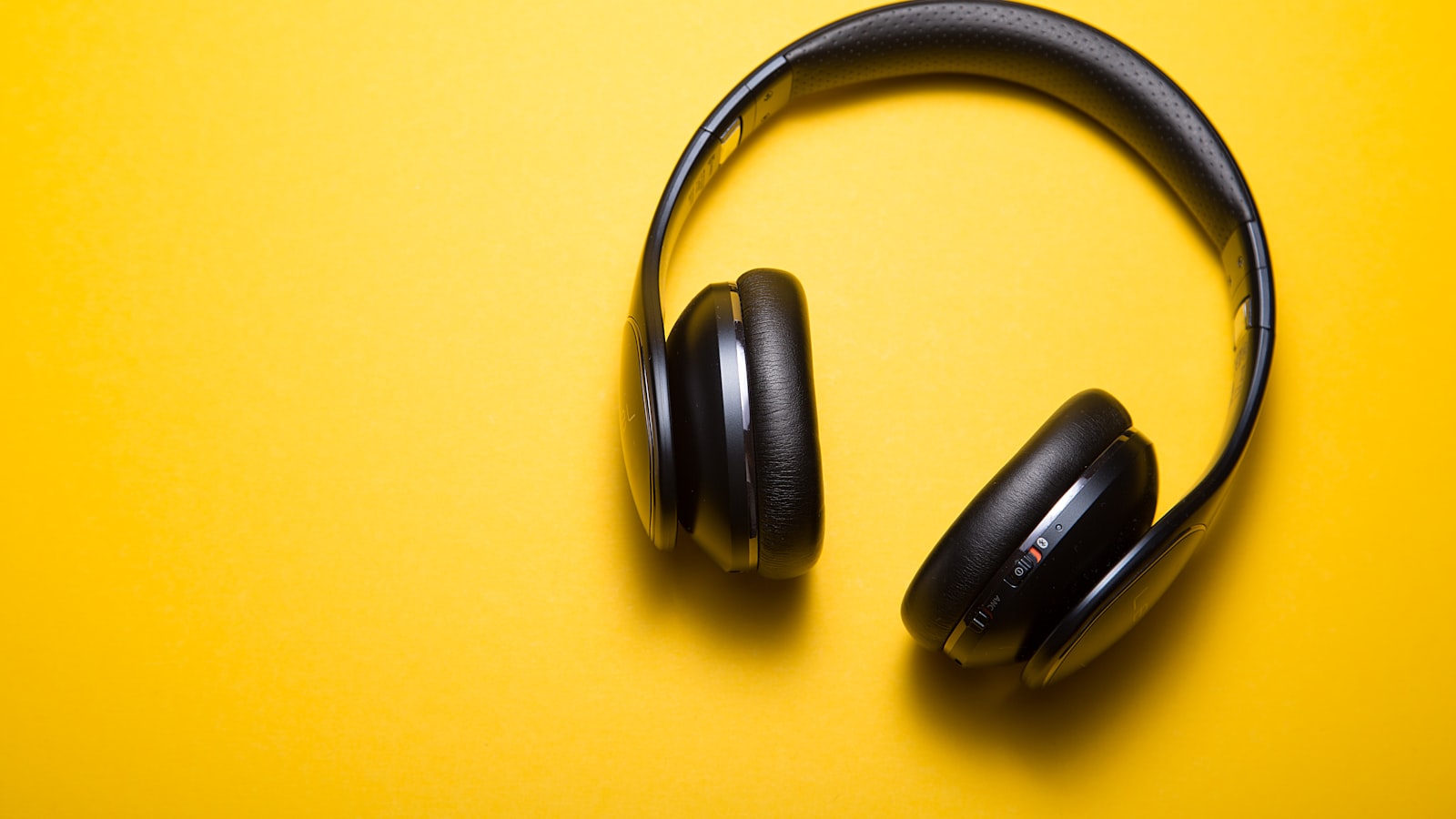 Someone wearing headphones while walking outdoors on a bright day.