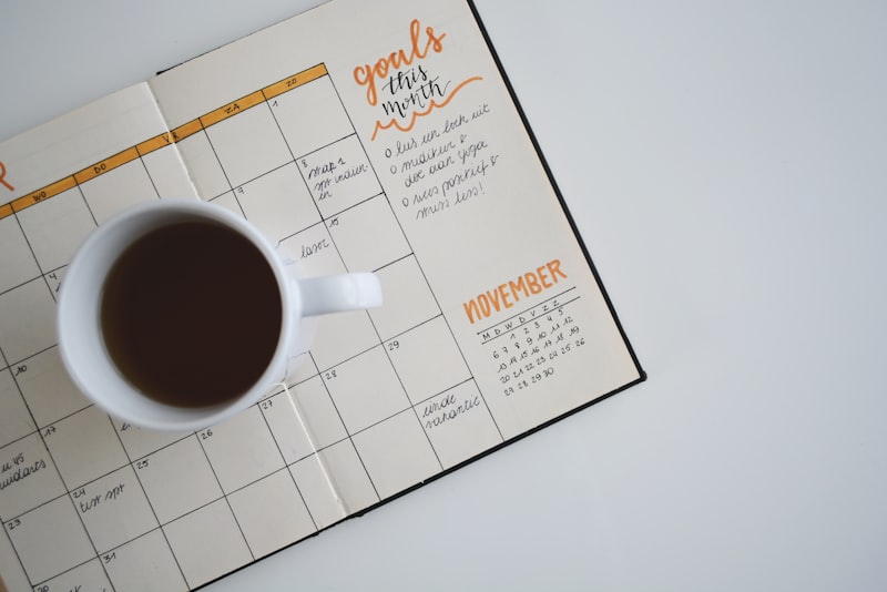 An open paper calendar with dates marked, sitting on a wooden desk.