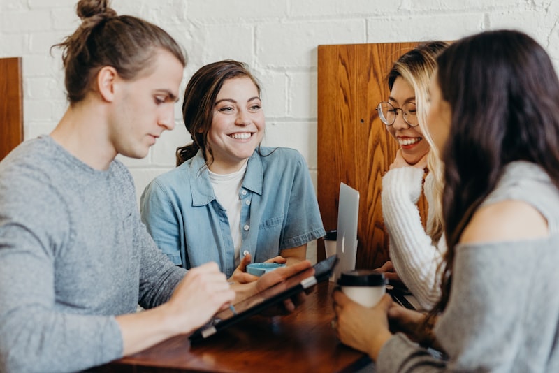 A group of friends talking together around a table outdoors.